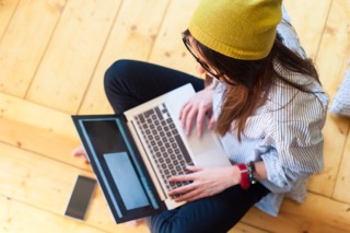 Woman cross-legged on the floor working on a laptop